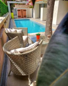 duas cadeiras de vime sentadas ao lado de uma piscina em Hôtel Beau Soleil em Le Lavandou