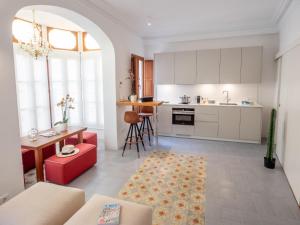 a kitchen with white cabinets and a red couch at Es Palauet Brandnew one suite apartment in Ibiza center in Ibiza Town
