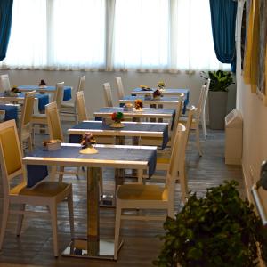 - une rangée de tables et de chaises dans une chambre avec fenêtres dans l'établissement Aparthotel Tiziano, à Grado