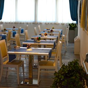 a row of tables and chairs in a room with windows at Aparthotel Tiziano in Grado