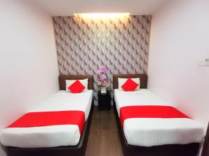 two beds in a room with red pillows at Palazzo Hotel Kulai in Kulai