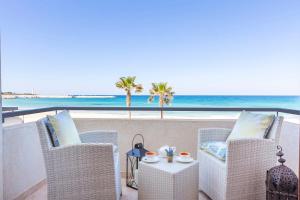 a patio with chairs and a table with a view of the beach at Mira Spiaggia in San Vito lo Capo