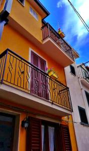 a yellow building with a balcony and windows at Alley 8 in Scilla