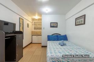 een kleine kamer met een bed en een televisie bij Pension Inn Marilao in Lias