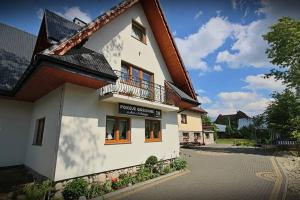 Un edificio blanco con un balcón en una calle. en Pokoje Gosinne U Ani i Andrzeja, en Małe Ciche