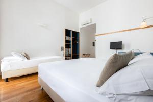 two beds in a bedroom with white walls and wooden floors at Hotel Piazza Bellini & Apartments in Naples