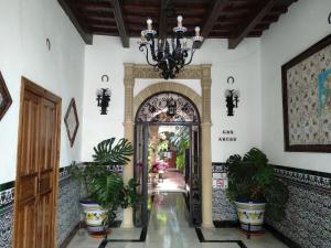 a hallway with an archway with plants and a chandelier at Pensión Los Arcos in Córdoba