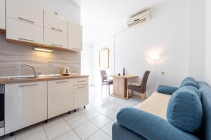 a living room with a blue couch and a kitchen at Apartments Radulj in Goveđari