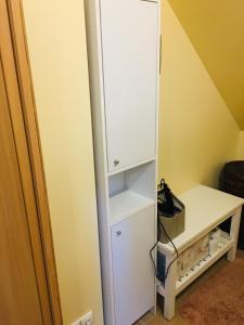 a closet with a white cabinet next to a desk at River Apartments in Šilutė