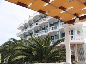 un gran edificio blanco con palmeras delante en Hotel Dodona, en Sarandë