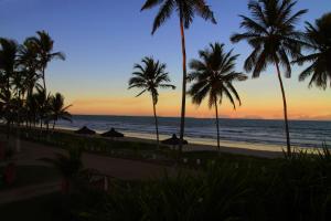 una vista de la playa al atardecer con palmeras en POUSADA STELLA MARIS, en Canavieiras