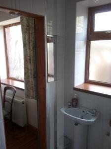 a bathroom with a sink and two windows at Rosslare Strand Rooms Only Accommodation in Rosslare