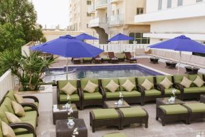 a patio with couches and umbrellas next to a pool at Mangrove Hotel in Ras al Khaimah