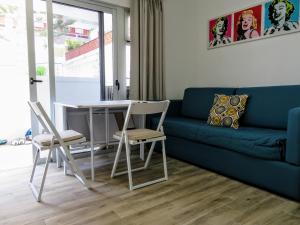 sala de estar con sofá azul, mesa y sillas en Casa Bruna Beach House, en Playa del Inglés