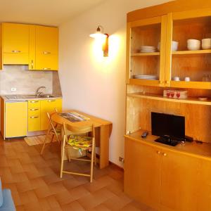 a kitchen with yellow cabinets and a table with a television at La casa di Pila in Pila