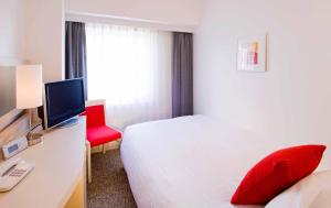 東京にあるレンブラントスタイル東京西葛西のベッドと赤い椅子が備わるホテルルームです。