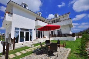 a white house with a table with a red umbrella at Sea Daughter's Homestay in Huxi