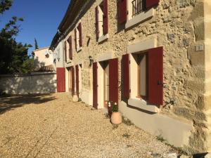 um edifício com portas vermelhas e algumas plantas ao lado em la maison ocre em Saint-Julien-de-Briola