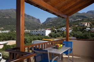 a table and chairs on a balcony with mountains at Morpheas Apartments in Plakias