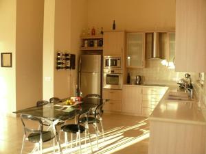 a kitchen with a glass table and chairs in it at Happy Trails Pomos Panoramic Villa in Pomos