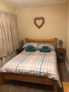 a bedroom with a bed with a heart sign on the wall at The Downs, Thurlestone, South Devon, close to several beaches in Kingsbridge