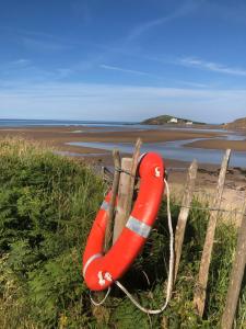 a red life preserver sitting on a fence at the beach at The Downs, Thurlestone, South Devon, close to several beaches in Kingsbridge