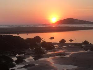 a sunset on the beach with a mountain in the background at The Downs, Thurlestone, South Devon, close to several beaches in Kingsbridge