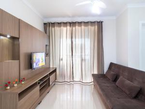 sala de estar con sofá marrón y TV en Aluguel Apartamento 2 quartos sendo 1 suíte Bombas/SC, en Bombinhas