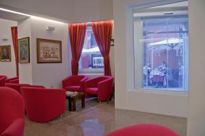 uma sala de espera com cadeiras vermelhas, uma mesa e uma janela em Hotel Italia em Cagliari