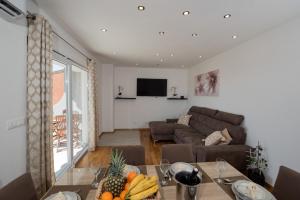 uma sala de estar com um sofá e uma mesa com fruta em Apartment Ankica with beautiful sea view em Podstrana
