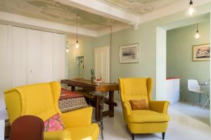 un soggiorno con sedie gialle e tavolo in legno di Duomo Luxury Suite - by MyHomeInComo a Como