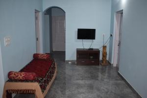 a living room with a couch and a flat screen tv at Srishti Homestay in Madikeri