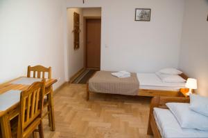 a room with two beds and a table and chairs at Pokoje Gościnne Dom św. Szymona in Kraków