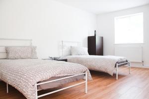 two beds in a white room with wooden floors at Lux Apartment in Bangor