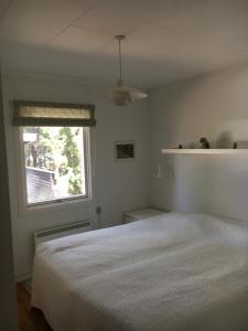 a bedroom with a white bed and a window at Midtvejshuset in Rønne