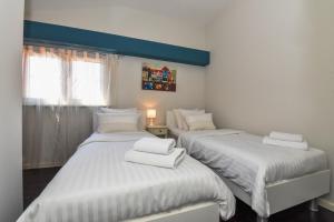 two beds in a room with white sheets at Rory Apartments in Zadar