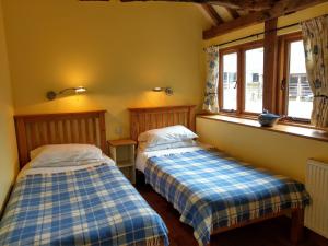 two beds in a room with two windows at White Pond Farm in Pishill