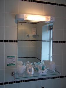 a mirror in a bathroom with items on a counter at Glenwood Guesthouse Betws-y-coed in Betws-y-coed +50 photos