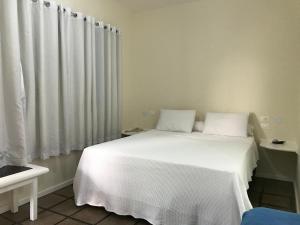 a bedroom with a white bed with white curtains at Pousada Agua Viva in Abraão