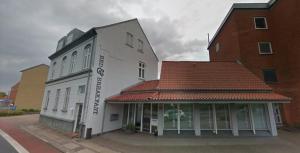 a white building with a red roof on a street at Bed & Breakfast Holstebro in Holstebro