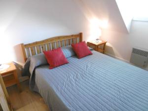 1 dormitorio con 1 cama con 2 almohadas rojas en Maisonnette Youenn, en Sarzeau
