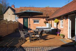 a patio with a table and chairs and an umbrella at West Mead Cottage in Wirral