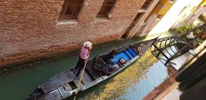 een vrouw peddelt een boot in een kanaal bij Scalon del Doge in Venetië
