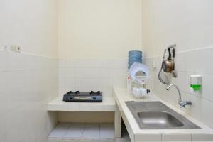 a white tiled kitchen with a sink and a sink at RedDoorz near Institut Pertanian Yogyakarta in Yogyakarta