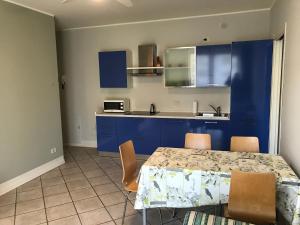 a kitchen with blue cabinets and a table with chairs at Grazioso Bilocale Metrò/Centro in Brescia