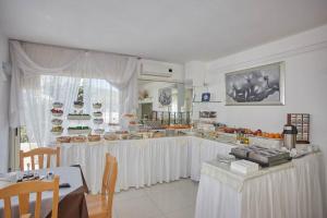una cucina con tavoli bianchi e bancone con cibo di B&B Ala Marina a Peschici