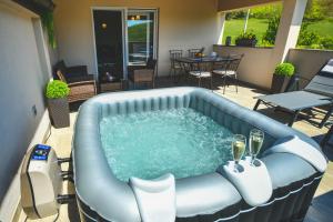 a hot tub on a patio with a table and chairs at CAMBI LUX APARTMENT in Otok