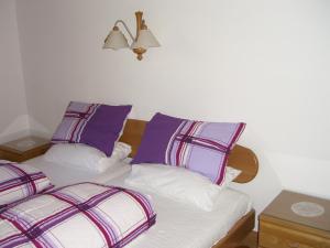 a bed with purple and white pillows in a room at Kaiserhof in Alpbach