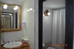 y baño con lavabo, espejo y ducha. en Apart Bungalows Amulen en San Carlos de Bariloche