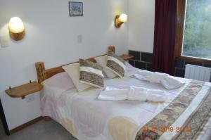 Un dormitorio con una cama con sábanas y almohadas blancas. en Apart Bungalows Amulen, en San Carlos de Bariloche